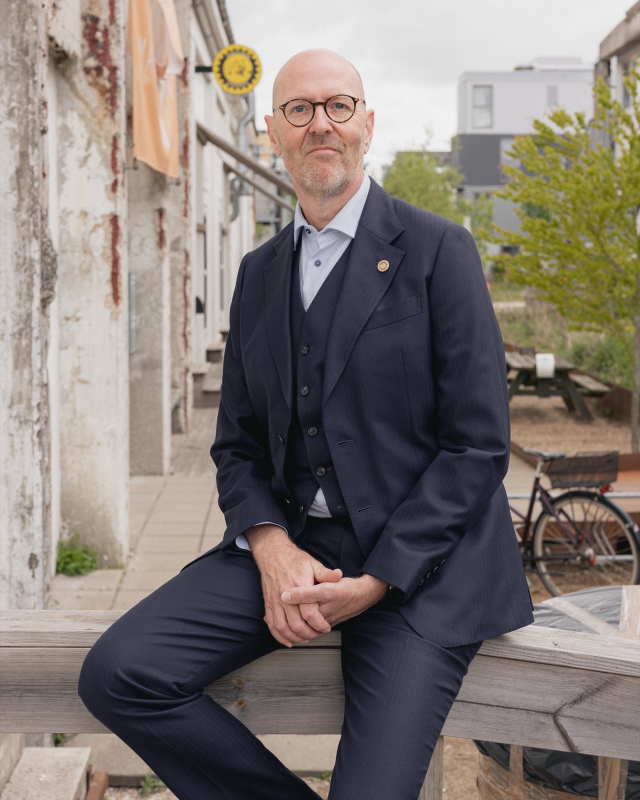 Per Beining sitting on a wooden railing in a Copenhagen courtyard