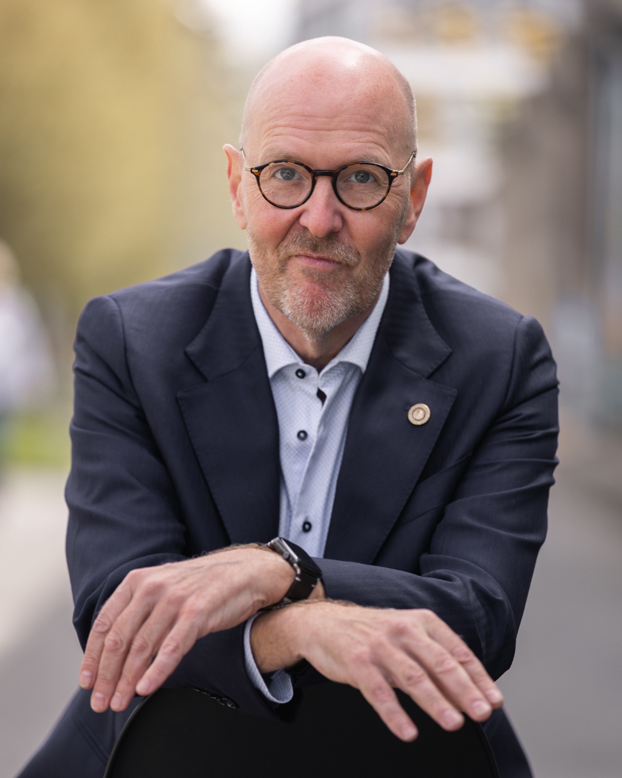 Per Beining smiling, leaning on a chair on a Copenhagen street