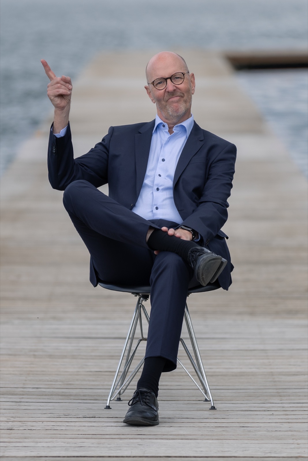 Per Beining sitting on a jetty by the water, raising one finger to make a point