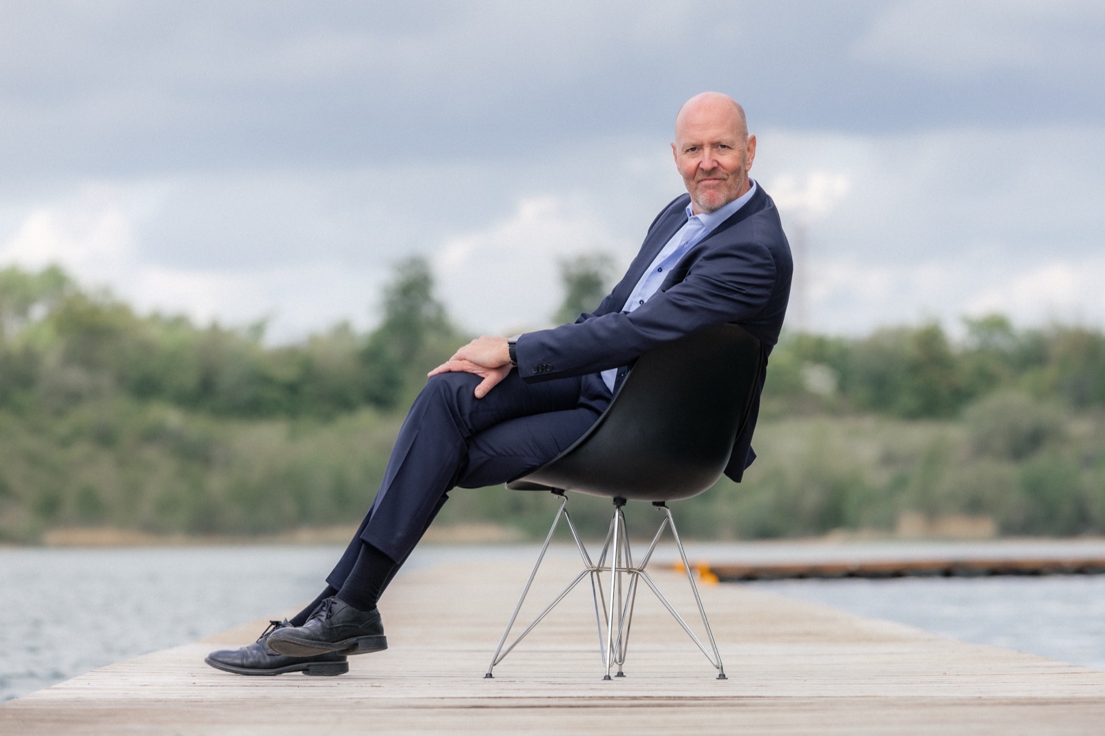 Per Beining leaning back in a chair on a lakeside jetty, relaxed and smiling